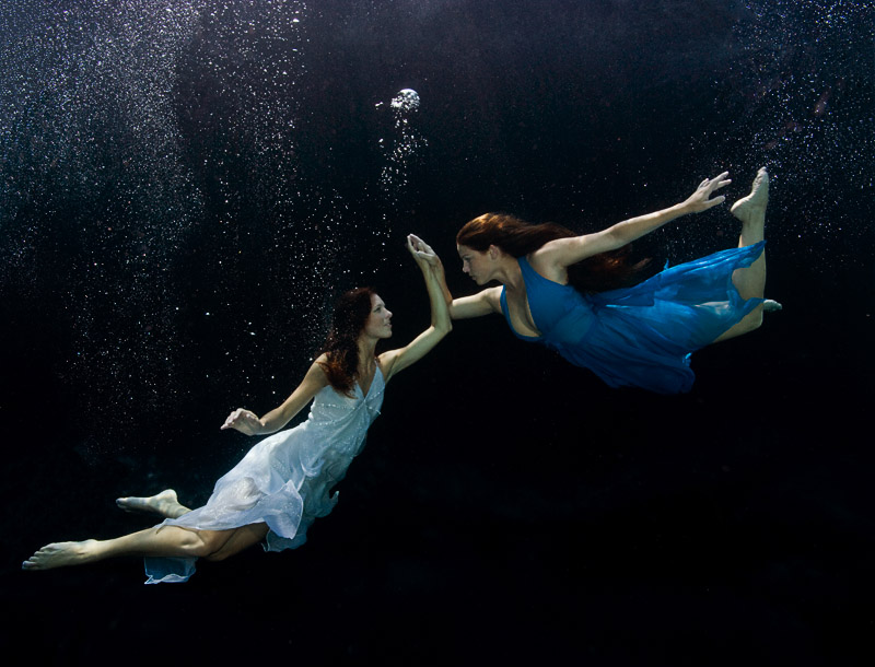 Two women touching underwater